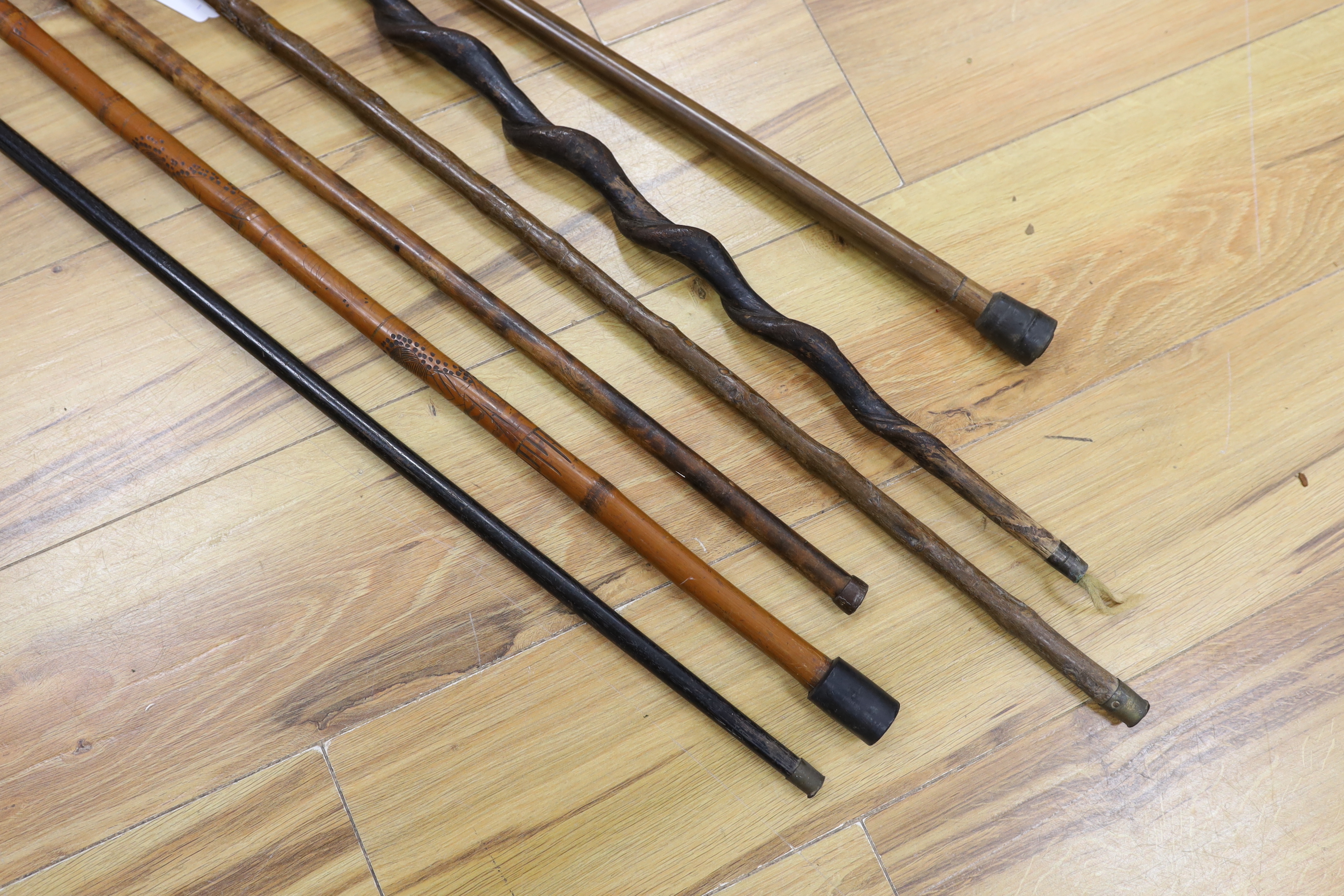 Six assorted walking sticks: a spiral carved cane, a silver mounted, a horn handled, a carved dog handled and a carved horse handled walking stick